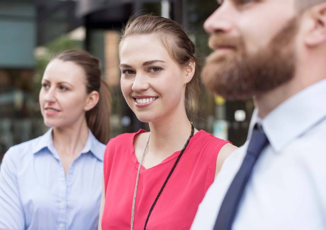 Colleagues chatting outdoors, one smiling at the camera